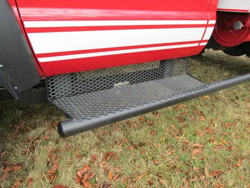 Exterior view of small fire truck showing cab, body compartments, and wheel/tire area.