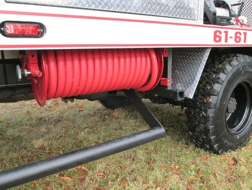 Exterior view of small fire truck showing cab, body compartments, and wheel/tire area.