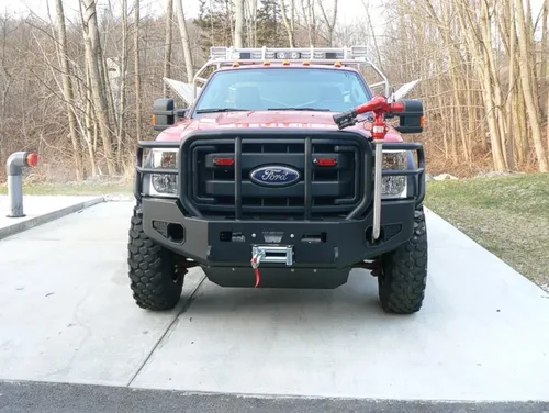 Exterior view of small fire truck showing cab, body compartments, and wheel/tire area.