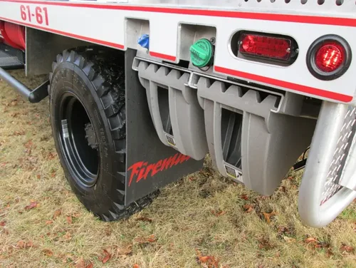 Exterior view of small fire truck showing cab, body compartments, and wheel/tire area.
