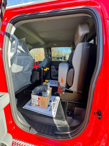 Interior side view through open rear door toward front seats and console.