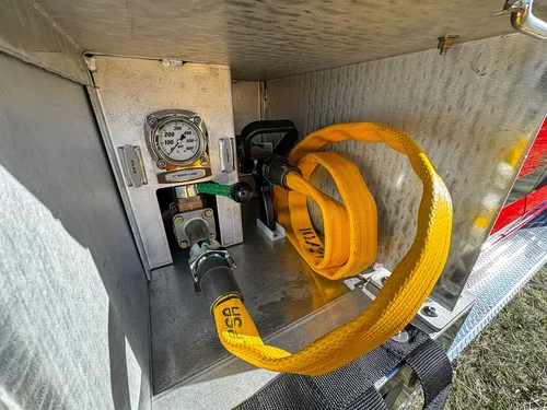 Compartment interior close-up with hose reel, valve, and gauge assembly.