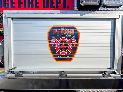Closed roll-up compartment door with large fire department emblem decal.