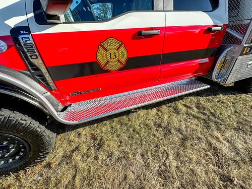 Cab side close-up with door emblem, side step, and lower rocker panel.