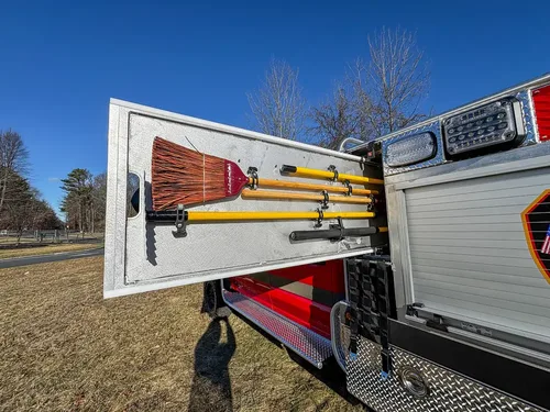 Open side door with mounted long-handled tools on interior brackets.