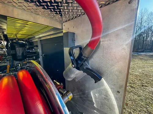 Pump area close-up with red hose, coupling, and nearby plumbing.