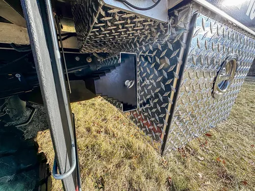 Lower side body close-up with diamond-plate compartment door and latch.