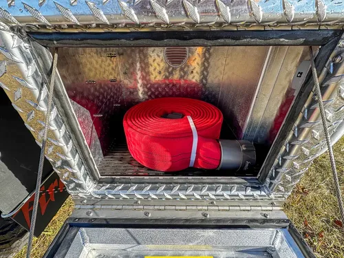 Compartment interior close-up with red rolled strap secured in storage.