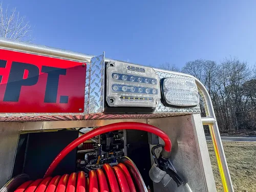 Upper body close-up with department lettering, scene light, and red hose.