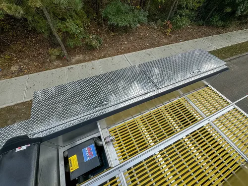 Top-side panel lifted over yellow grating and compartment access.