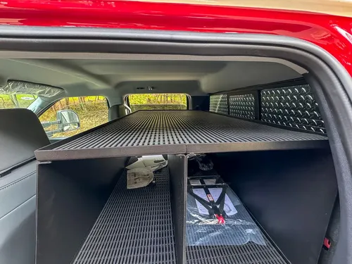 Rear shelf unit close-up behind front seats with mounted electronics.