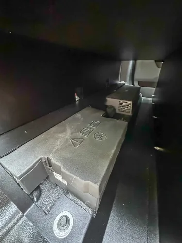 Lower rear compartment floor close-up with small warning stickers.