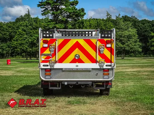Exterior view of small fire truck showing cab, body compartments, and wheel/tire area.