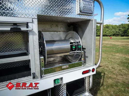 Exterior view of small fire truck showing cab, body compartments, and wheel/tire area.