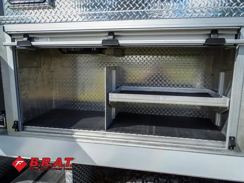 Exterior view of small fire truck showing cab, body compartments, and wheel/tire area.