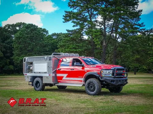 Exterior view of small fire truck showing cab, body compartments, and wheel/tire area.
