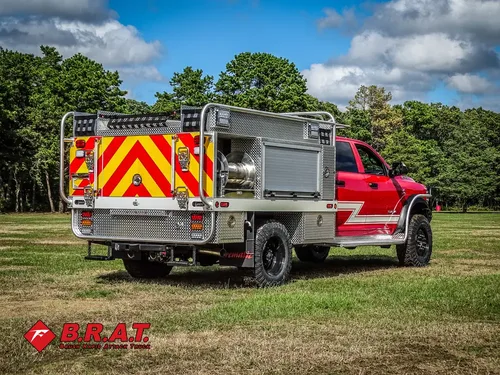 Exterior view of small fire truck showing cab, body compartments, and wheel/tire area.
