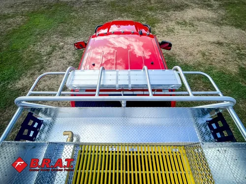 Exterior view of small fire truck showing cab, body compartments, and wheel/tire area.