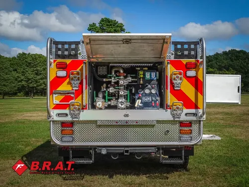 Exterior view of small fire truck showing cab, body compartments, and wheel/tire area.
