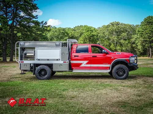 Exterior view of small fire truck showing cab, body compartments, and wheel/tire area.