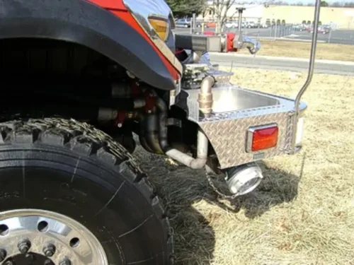 Exterior view of small fire truck showing cab, body compartments, and wheel/tire area.