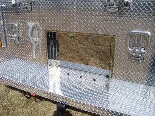 Exterior view of small fire truck showing cab, body compartments, and wheel/tire area.