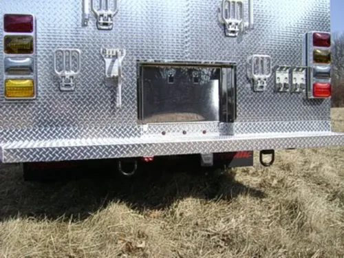 Exterior view of small fire truck showing cab, body compartments, and wheel/tire area.