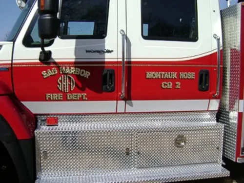 Exterior view of small fire truck showing cab, body compartments, and wheel/tire area.