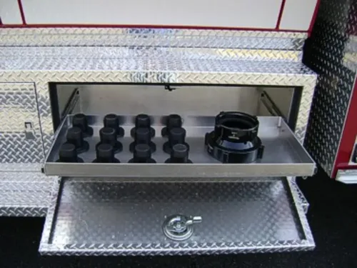 Exterior view of small fire truck showing cab, body compartments, and wheel/tire area.