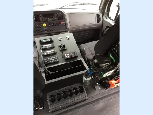 Exterior view of small fire truck showing cab, body compartments, and wheel/tire area.