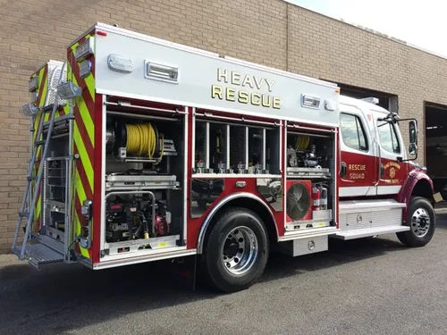 Exterior view of small fire truck showing cab, body compartments, and wheel/tire area.