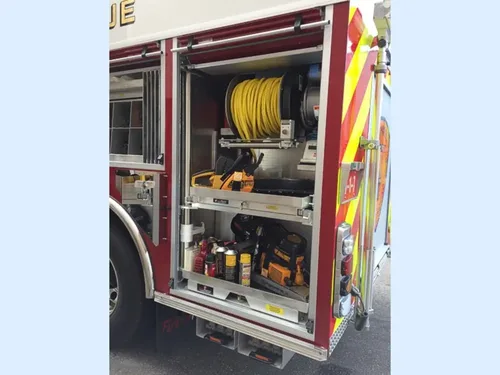 Exterior view of small fire truck showing cab, body compartments, and wheel/tire area.