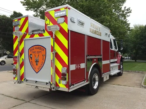 Exterior view of small fire truck showing cab, body compartments, and wheel/tire area.