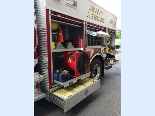 Exterior view of small fire truck showing cab, body compartments, and wheel/tire area.