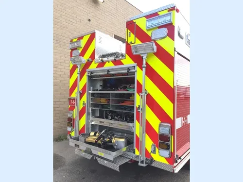 Exterior view of small fire truck showing cab, body compartments, and wheel/tire area.