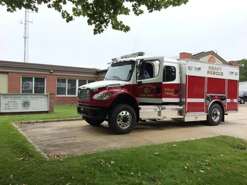 Exterior view of small fire truck showing cab, body compartments, and wheel/tire area.