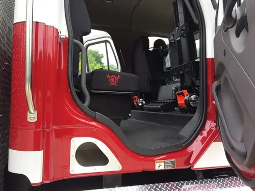 Exterior view of small fire truck showing cab, body compartments, and wheel/tire area.