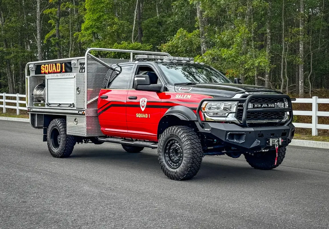 Front-left three-quarter exterior view of the small brush truck showing front bumper guard, side body, and wheel area.