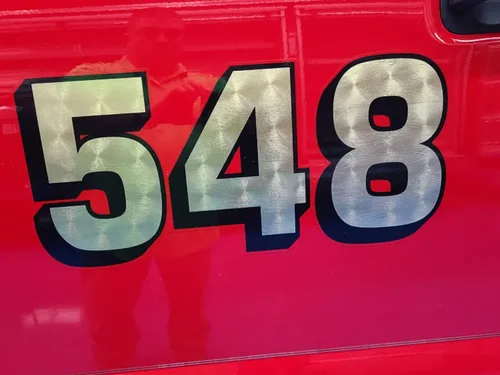 Exterior view of small fire truck showing cab, body compartments, and wheel/tire area.
