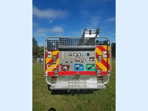 Exterior view of small fire truck showing cab, body compartments, and wheel/tire area.