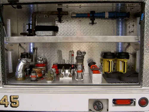 Exterior view of small fire truck showing cab, body compartments, and wheel/tire area.