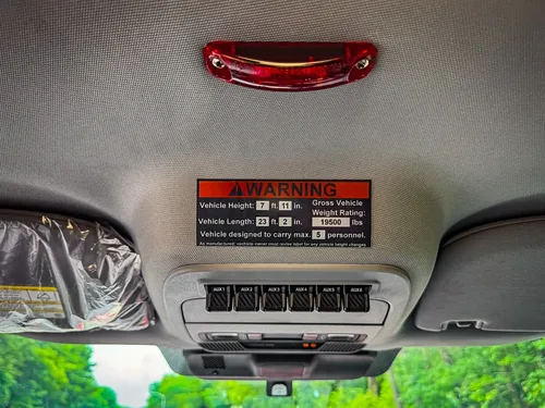 Headliner warning label and overhead light close-up inside cab.