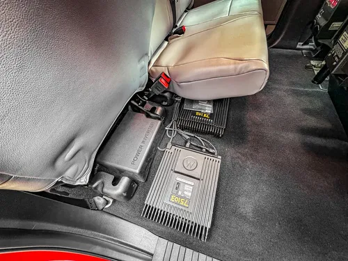 Rear footwell close-up with mounted equipment module behind seat.