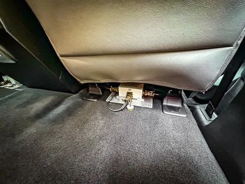 Rear footwell close-up with wiring and connectors beneath seat.