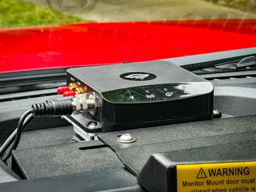 Dashboard-mounted electronics box close-up with cables connected.