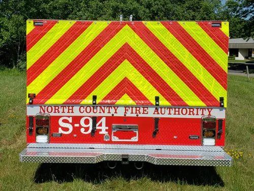 Exterior view of small fire truck showing cab, body compartments, and wheel/tire area.