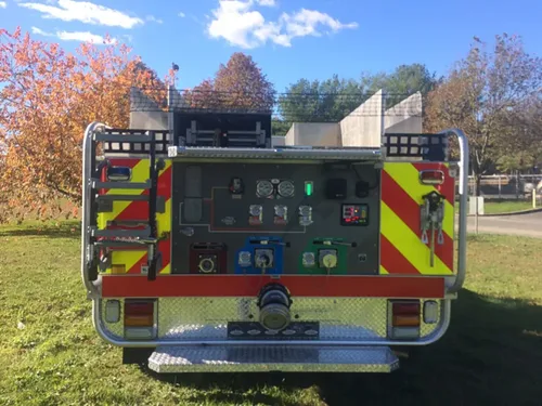 Exterior view of small fire truck showing cab, body compartments, and wheel/tire area.