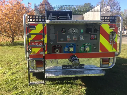 Exterior view of small fire truck showing cab, body compartments, and wheel/tire area.