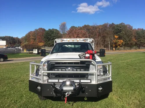 Exterior view of small fire truck showing cab, body compartments, and wheel/tire area.