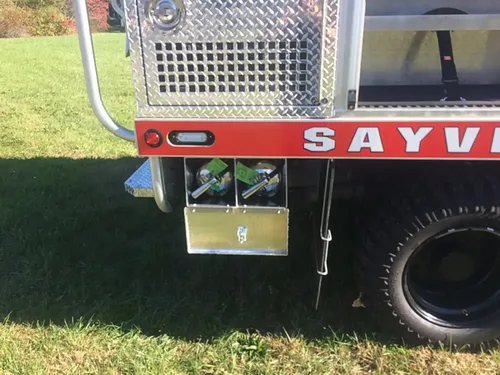 Exterior view of small fire truck showing cab, body compartments, and wheel/tire area.